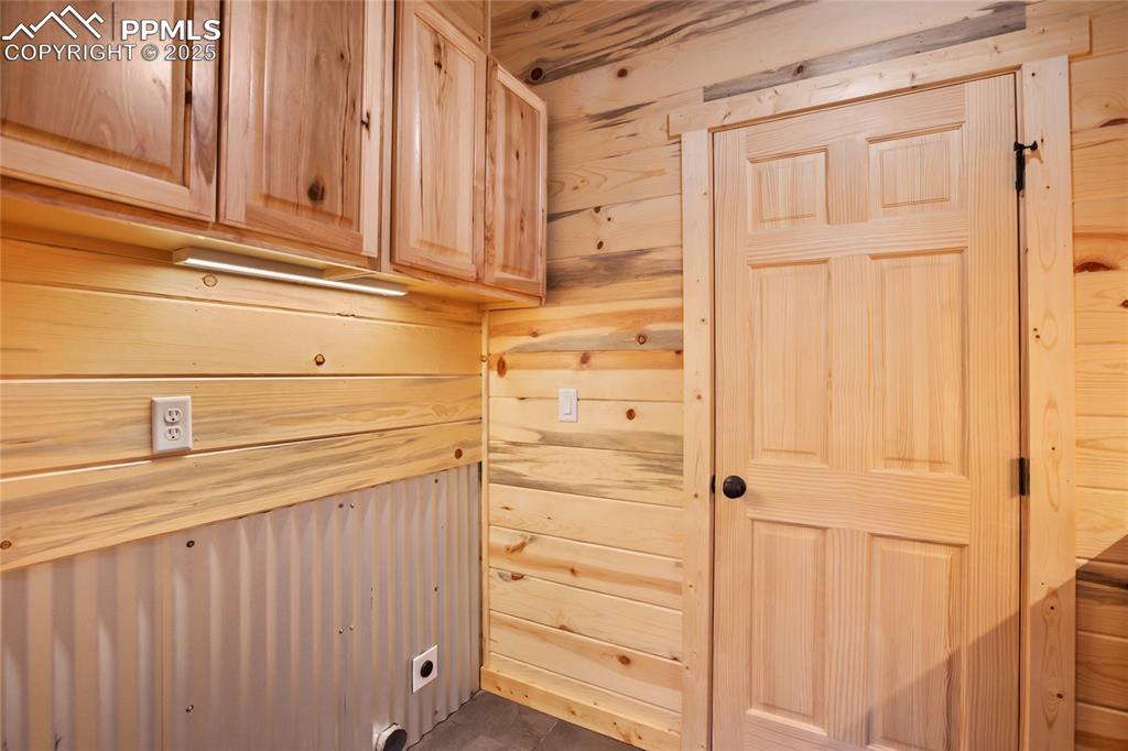 Laundry area featuring cabinet space, hookup for an electric dryer, and wooden walls