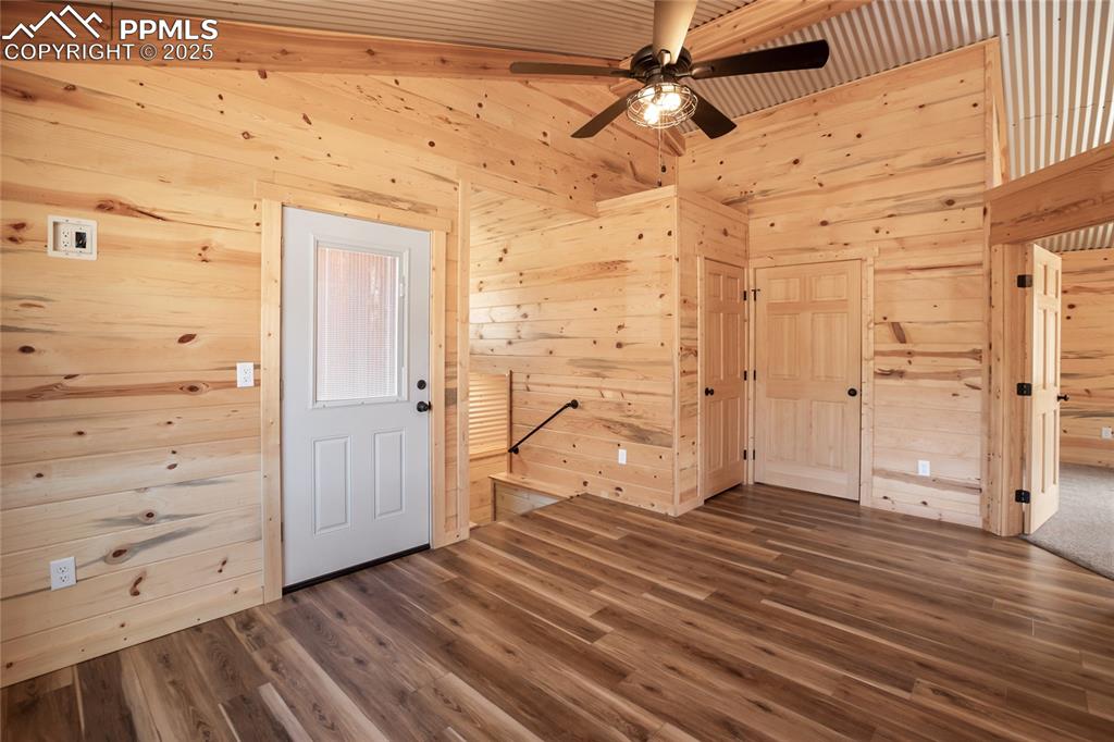 Upstairs walk out family room featuring pine paneling, LVP flooring, and a ceiling fan