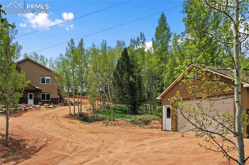 View of yard with a garage, an outdoor structure, and driveway