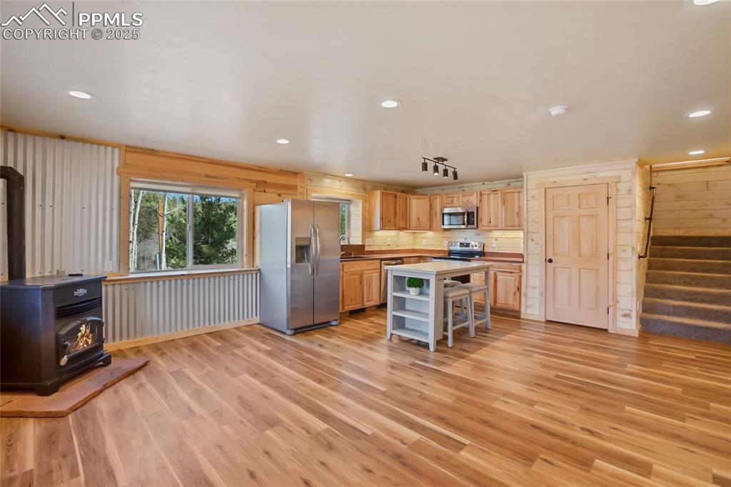 Kitchen with appliances with stainless steel finishes, pellet stove, LVP flooring, and a kitchen island