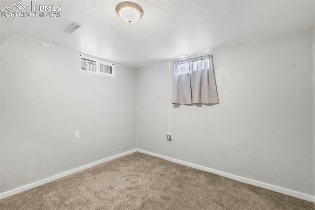Below grade area featuring carpet flooring, plenty of natural light, and a textured ceiling