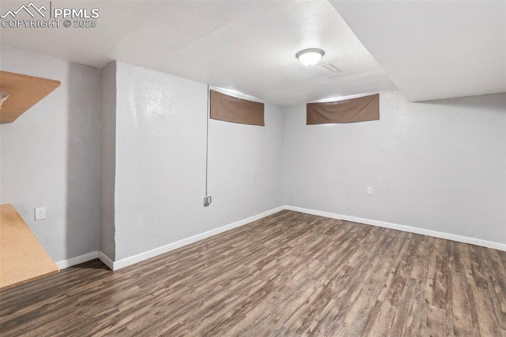 Finished below grade area featuring dark wood/laminate-style floors and baseboards
