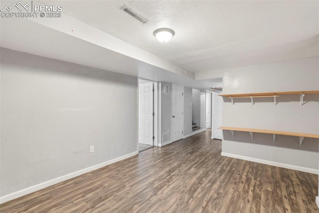 Finished basement with dark wood/laminate-style flooring and a textured ceiling