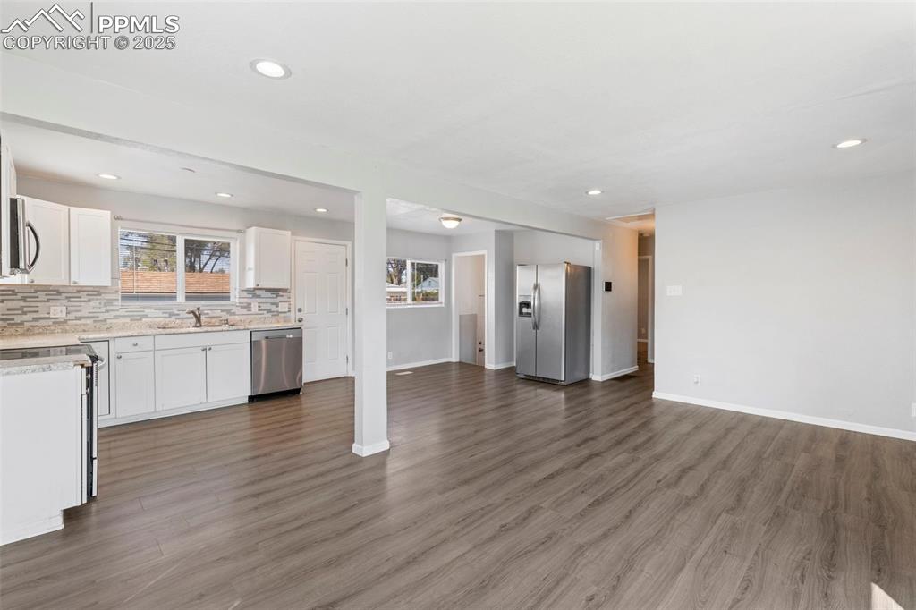 Unfurnished living room featuring plenty of natural light, recessed lighting, and dark wood/laminate finished floors