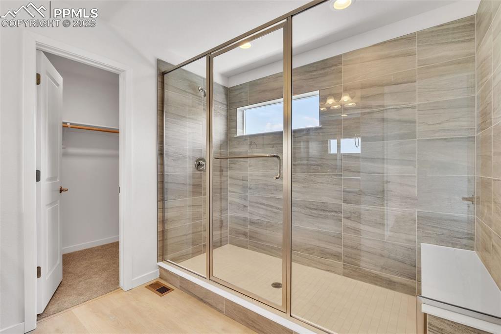 Full bathroom with a shower stall, a walk in closet, light wood-type flooring, and recessed lighting