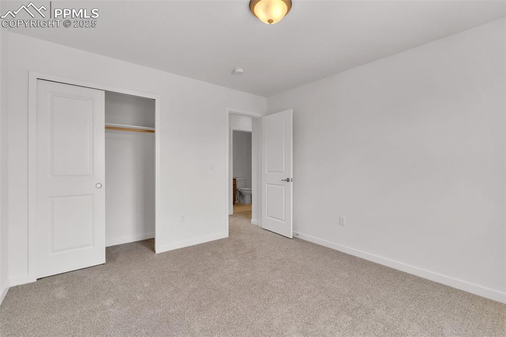 Unfurnished bedroom with light carpet and a closet
