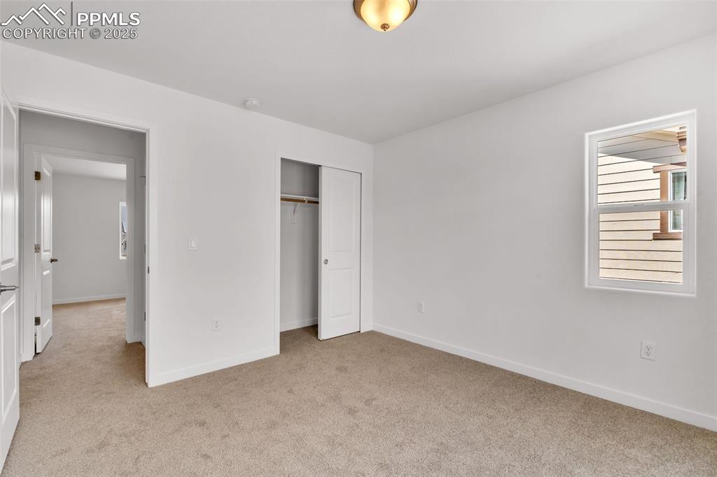 Unfurnished bedroom featuring light carpet and a closet