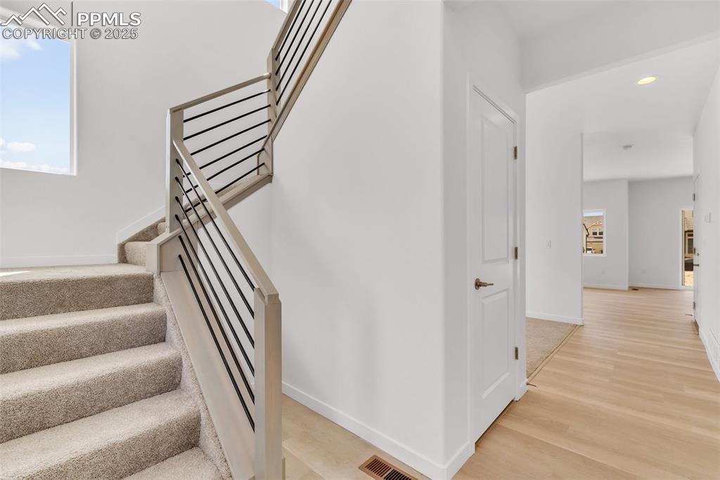 Stairs featuring wood finished floors and recessed lighting
