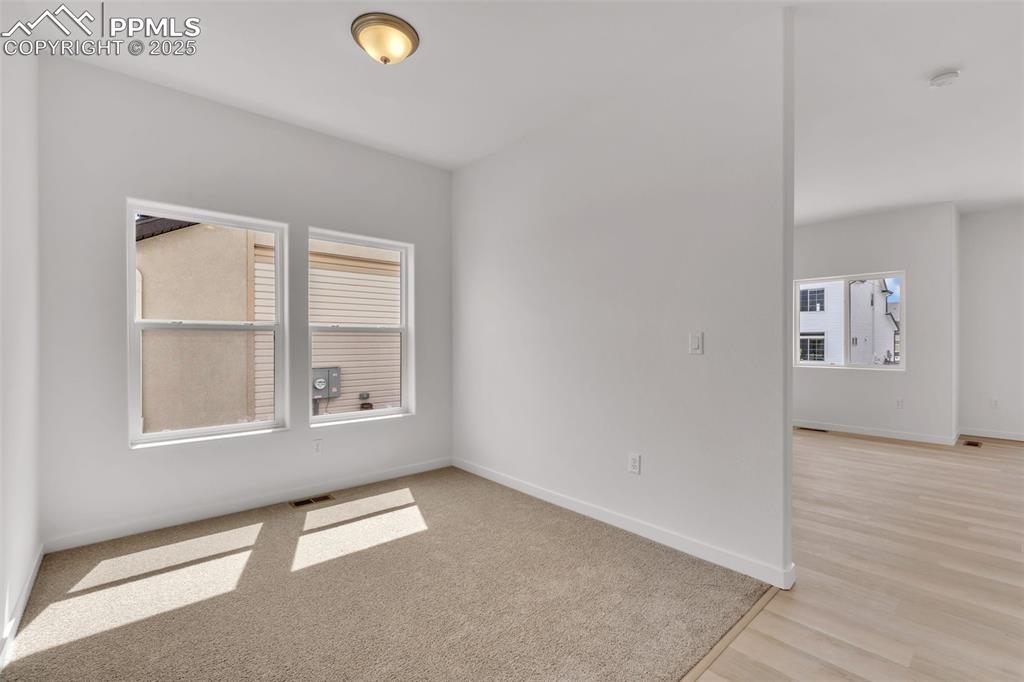 Unfurnished room featuring baseboards and light carpet