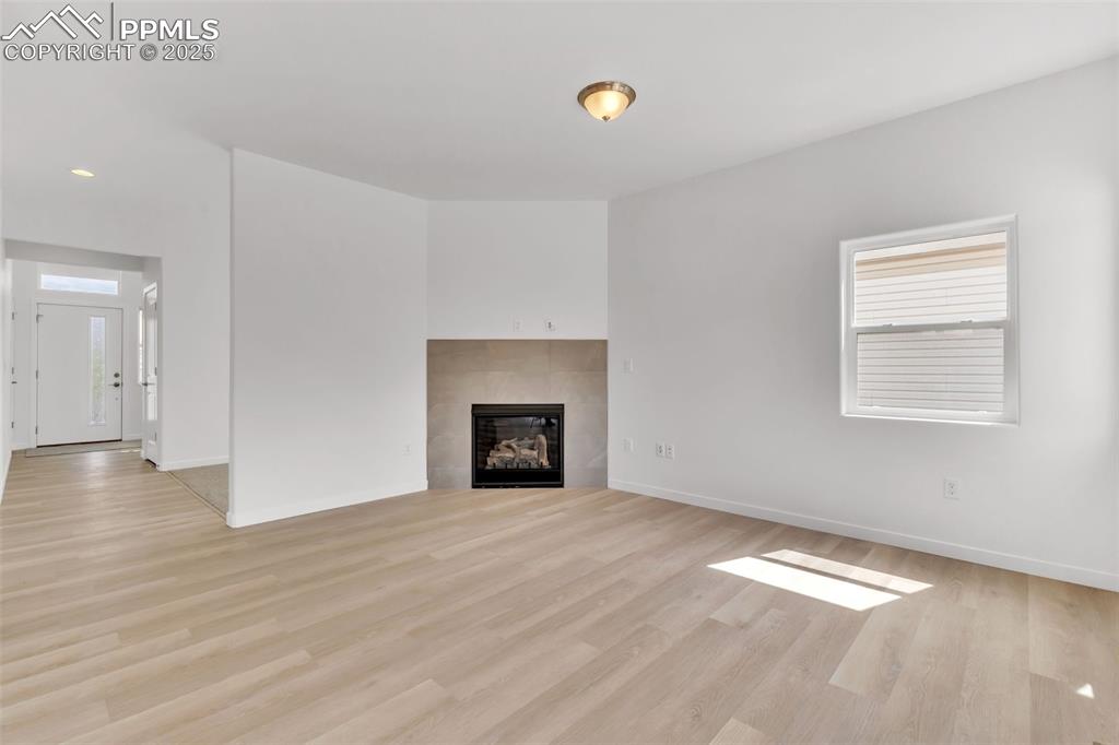 Unfurnished living room with a tile fireplace and light wood-style flooring