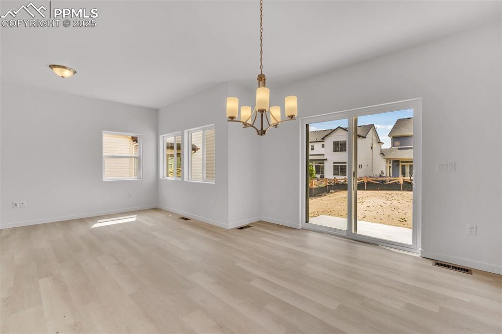 Unfurnished dining area featuring light wood finished floors and a chandelier