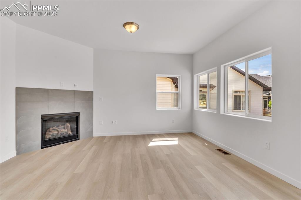 Unfurnished living room featuring a tile fireplace and light wood-type flooring