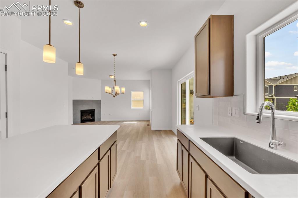 Kitchen with a tiled fireplace, light wood-style flooring, decorative light fixtures, recessed lighting, and open floor plan