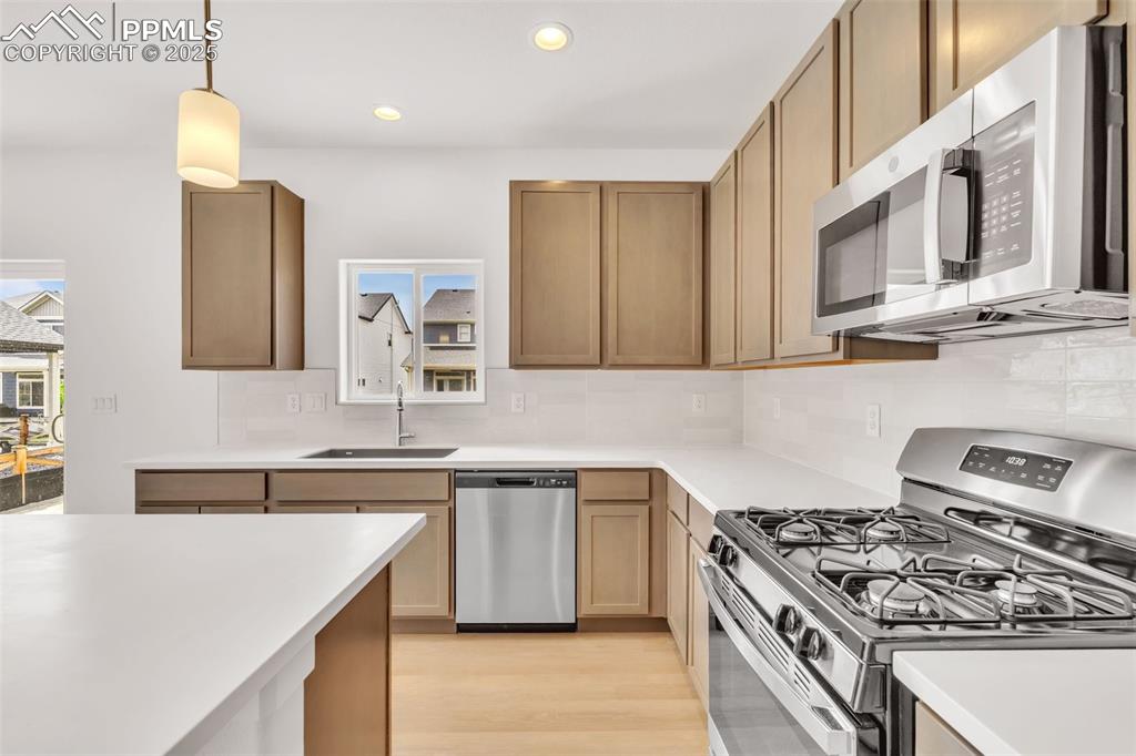 Kitchen with stainless steel appliances, decorative backsplash, pendant lighting, healthy amount of natural light, and recessed lighting
