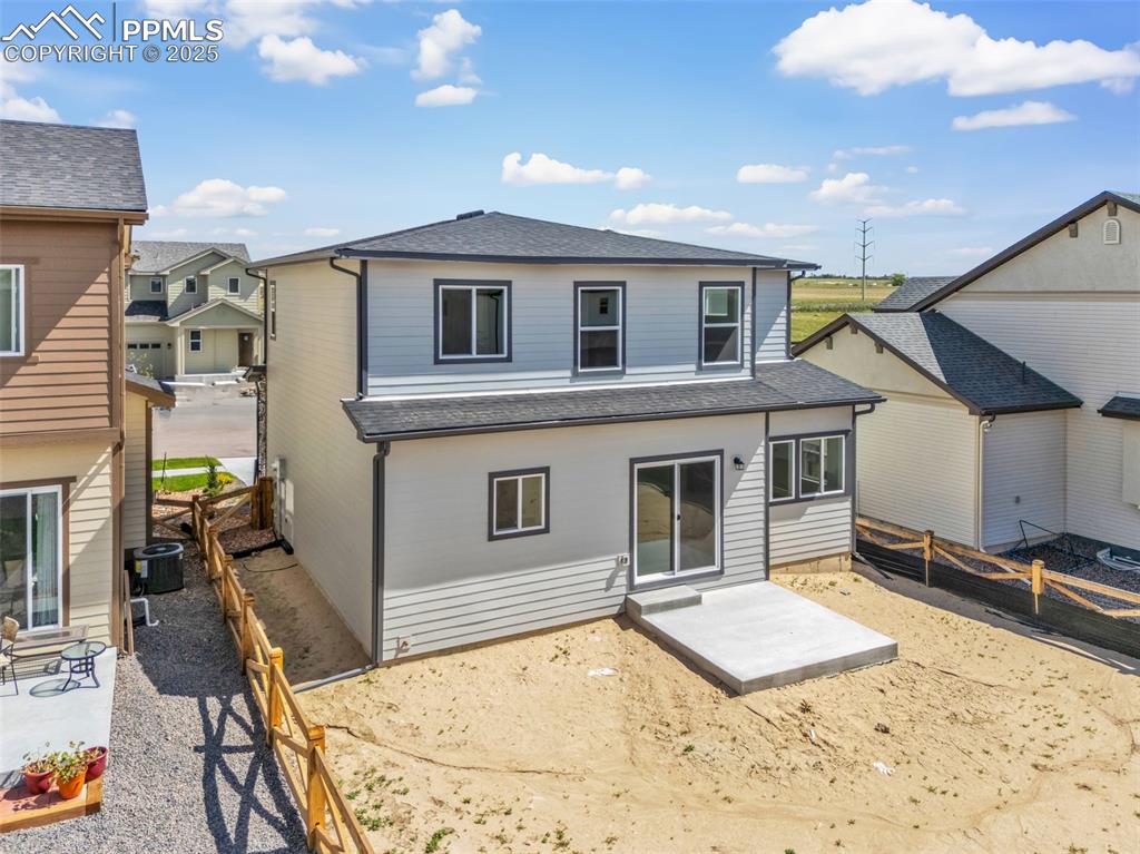 Rear view of house with a shingled roof, a patio, and a fenced backyard