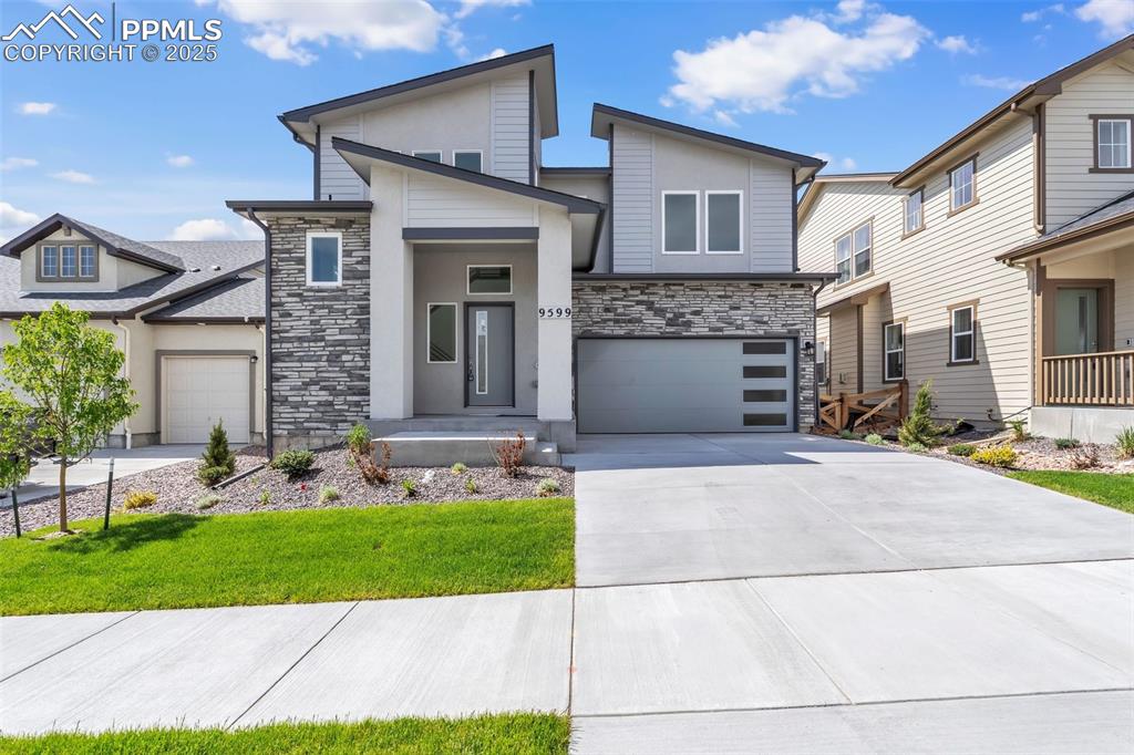 Modern home with stone siding, concrete driveway, a front yard, an attached garage, and stucco siding