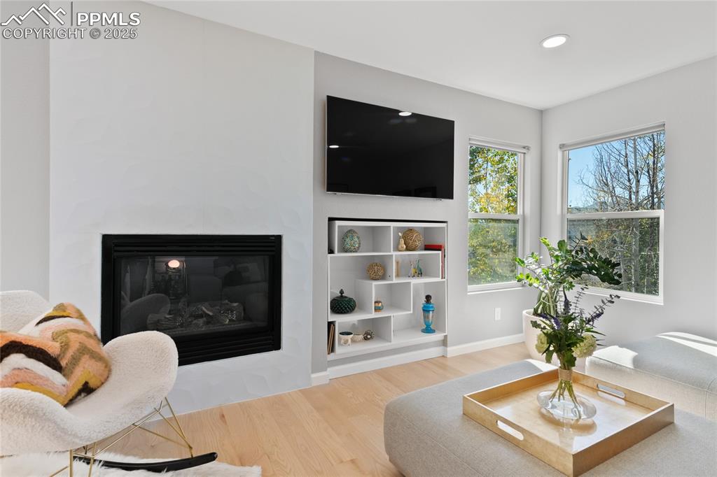 Living area with a glass covered fireplace, light wood-style floors, and recessed lighting