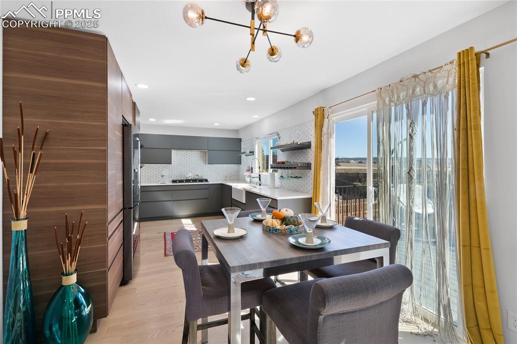 Dining area with light wood finished floors, a chandelier, and recessed lighting