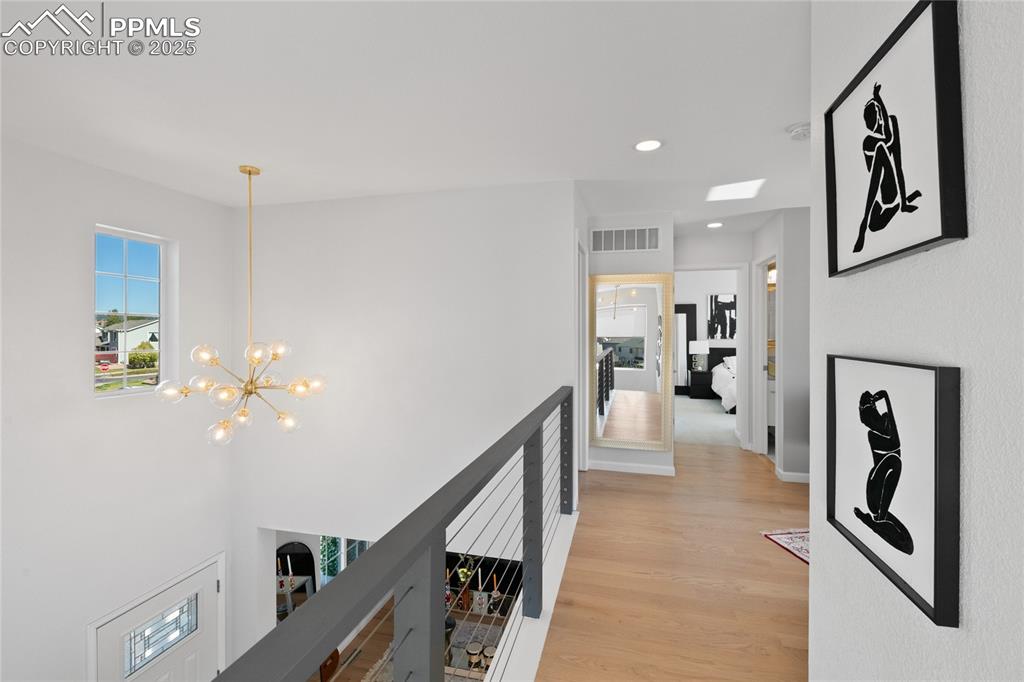 Hallway featuring recessed lighting, light wood-style flooring, a chandelier, and an upstairs landing
