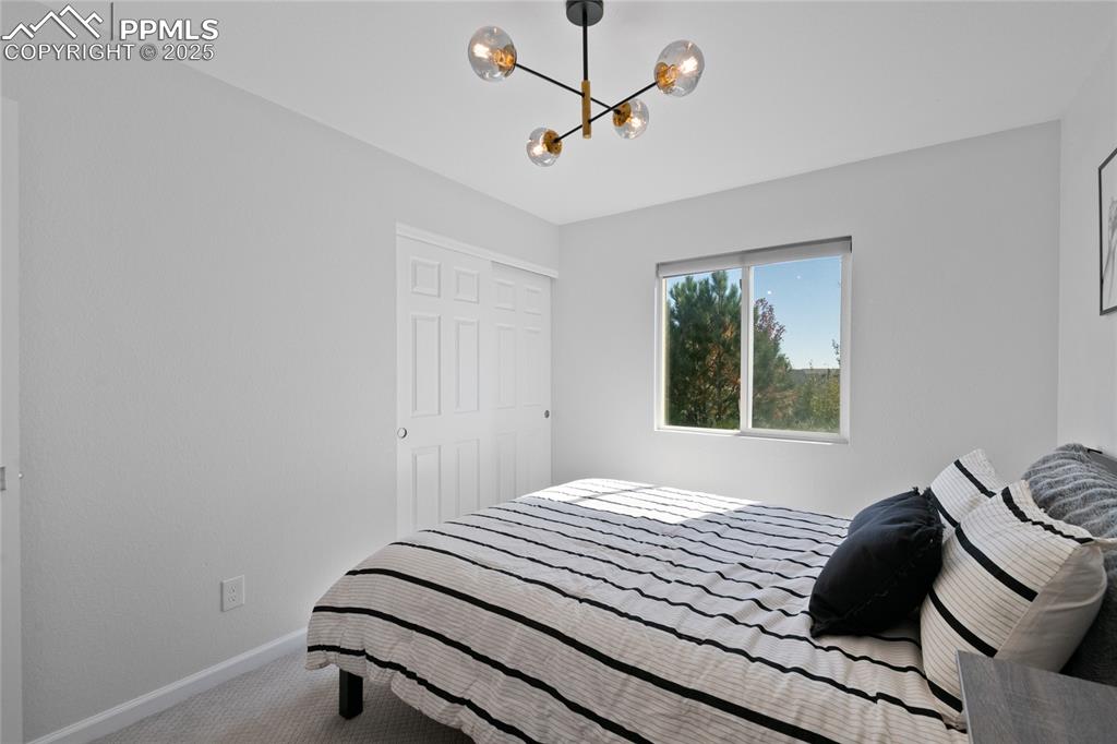 Carpeted bedroom with a chandelier and baseboards