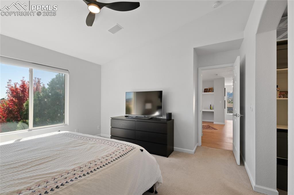 Bedroom with carpet, a ceiling fan, and vaulted ceiling