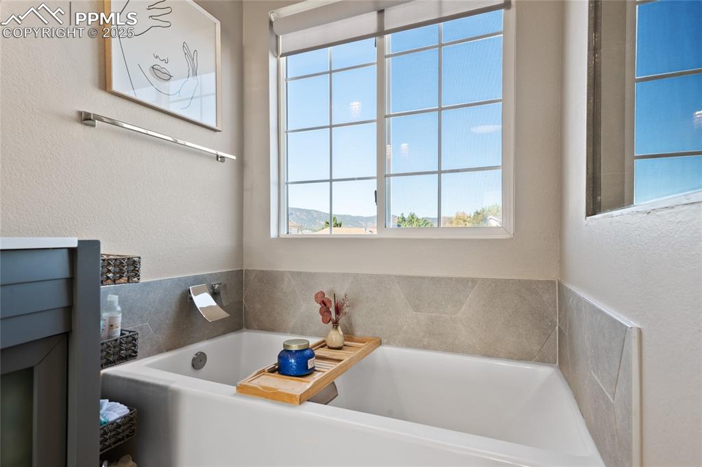 Bathroom with a garden tub and a textured wall