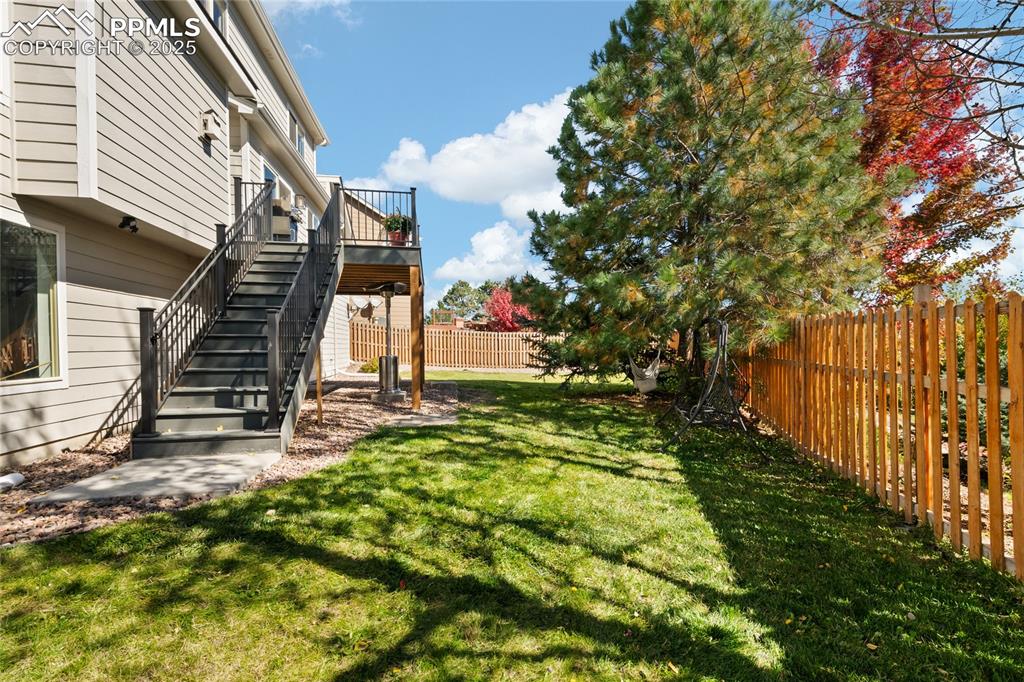 Fenced backyard featuring stairs, a deck, and a patio area
