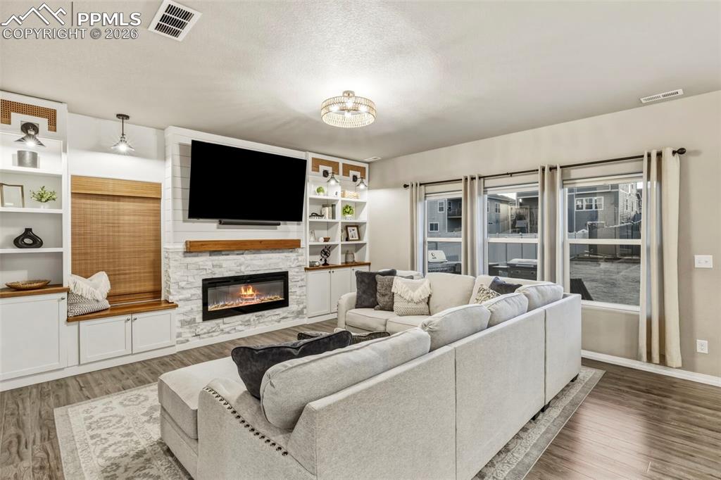 Living area featuring wood finished floors, a fireplace, and built in features