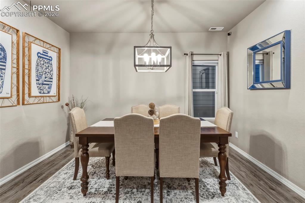 Dining space with wood finished floors and a chandelier