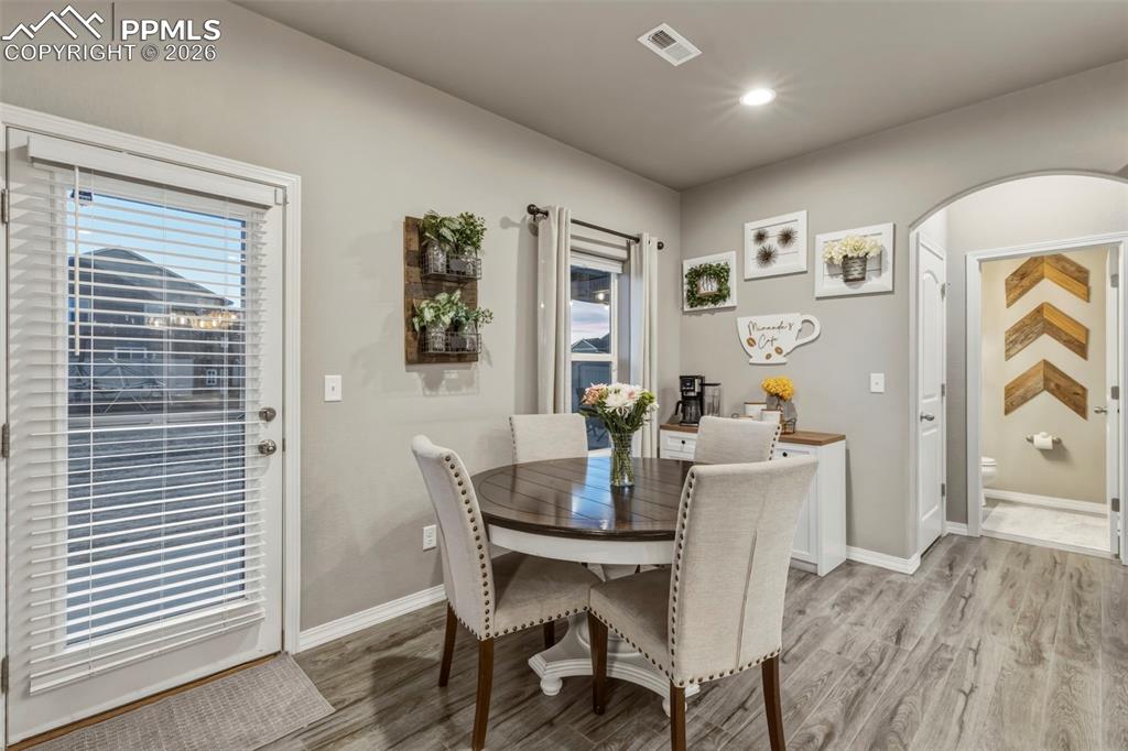 Dining room featuring arched walkways, light wood finished floors, and recessed lighting