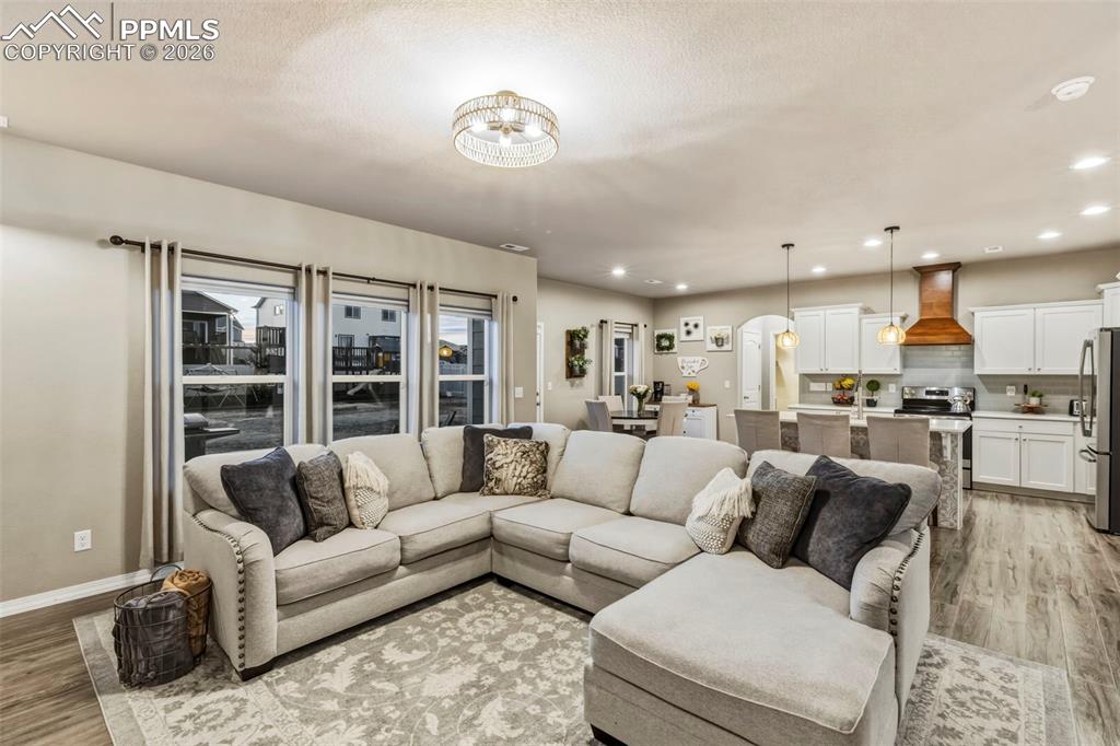 Living area featuring light wood-style flooring, arched walkways, and recessed lighting