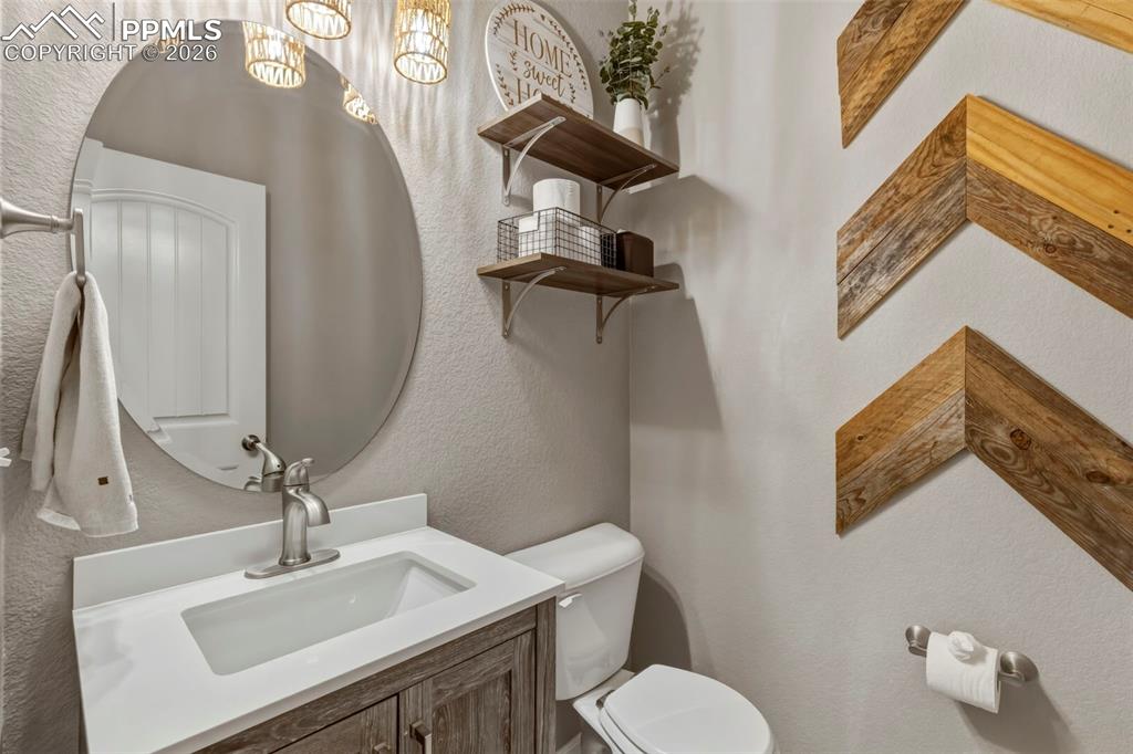 Half bath with a textured wall and vanity