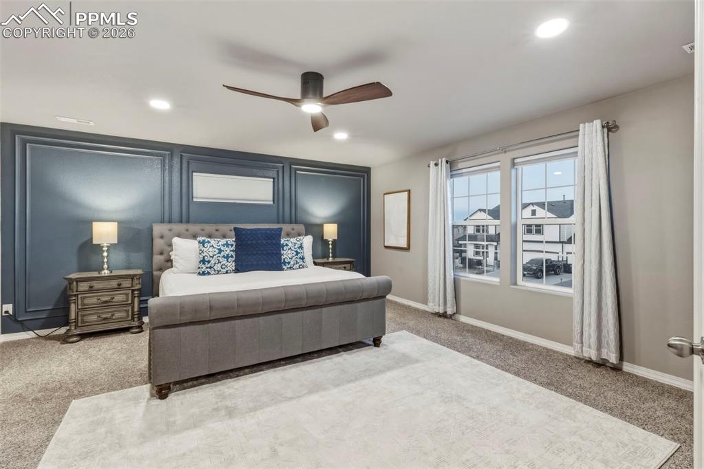 Bedroom with light carpet, recessed lighting, ceiling fan, and a decorative wall