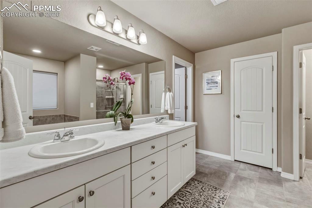 Full bath with double vanity and a shower stall