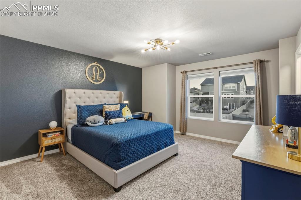 Bedroom featuring light carpet, a textured wall, and a textured ceiling