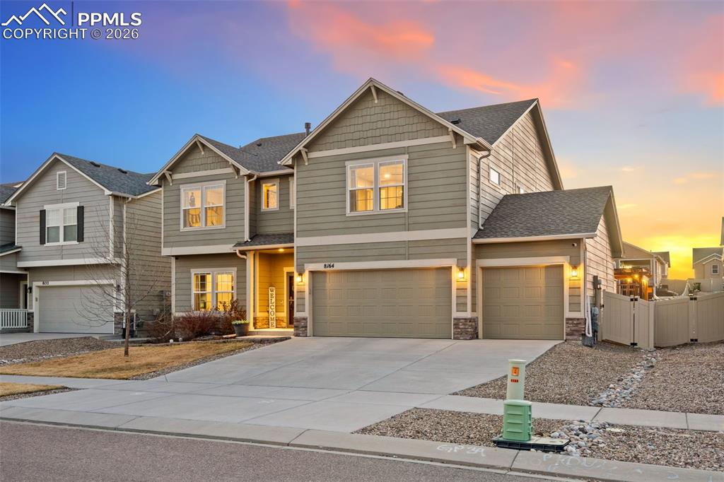 Craftsman-style house featuring an attached garage, driveway, stone siding, roof with shingles, and a residential view