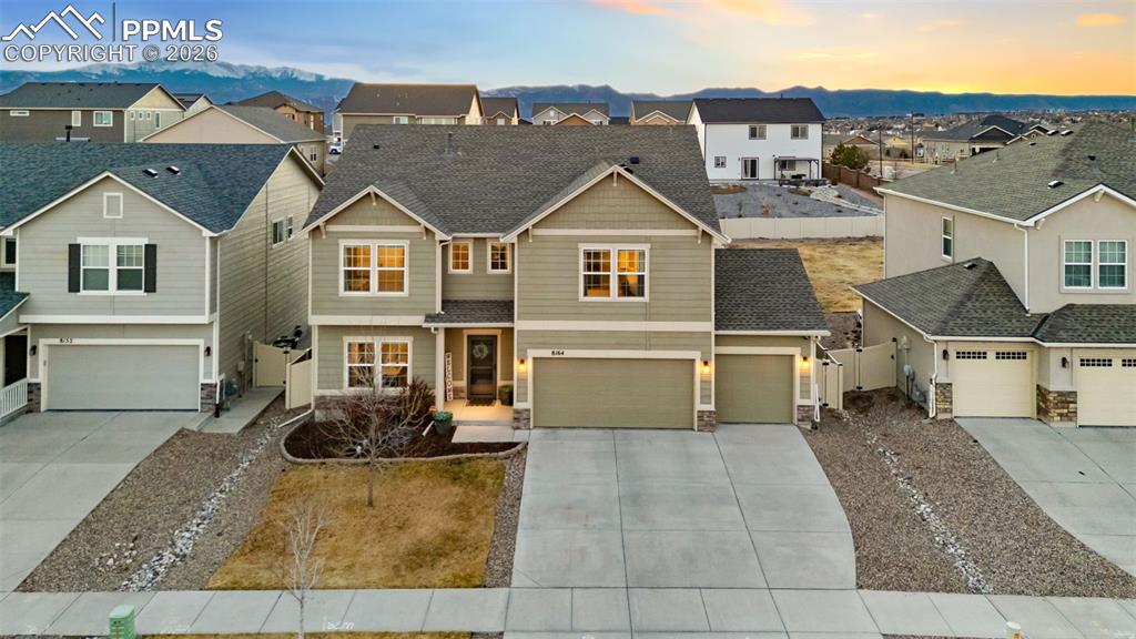 Craftsman house with stone siding, a residential view, concrete driveway, and an attached garage