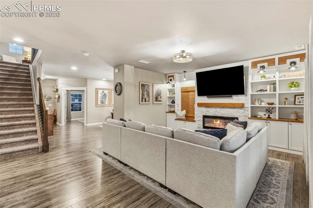 Living room with wood finished floors, a fireplace, and recessed lighting