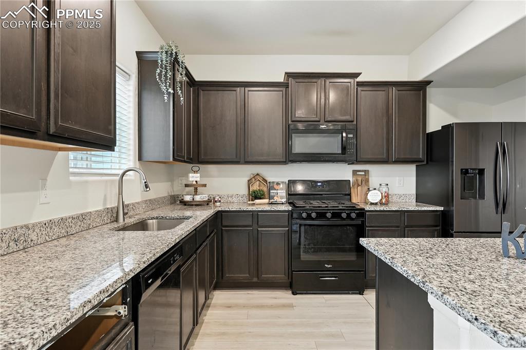 Well appointed kitchen that boasts rich espresso cabinetry, granite countertops, & black appliances