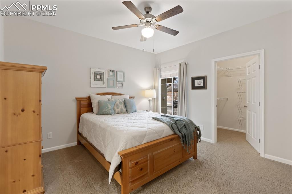Bedroom with a spacious closet, light carpet, and ceiling fan