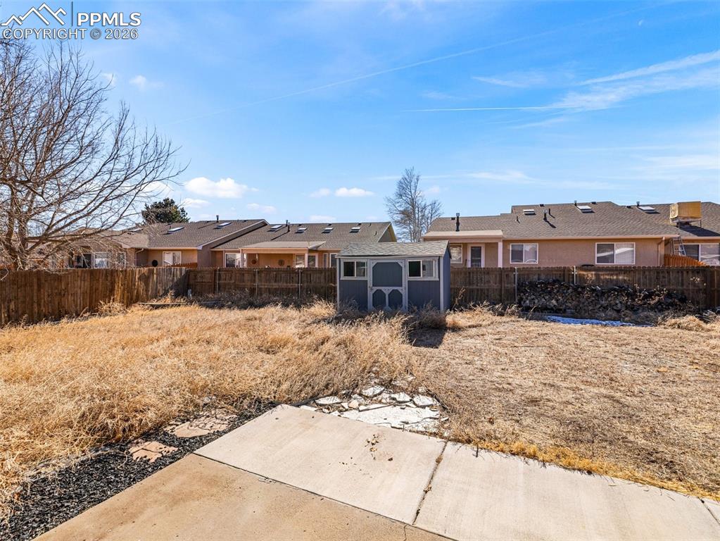 Fenced backyard featuring a residential view and a storage unit