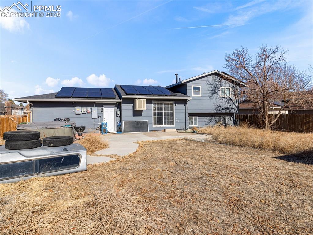 Rear view of house with roof mounted solar panels and a patio area
