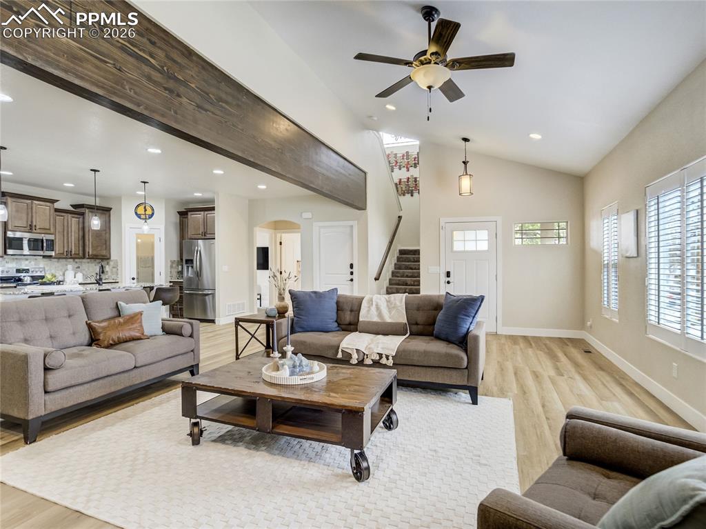 Open-concept living room with beam accent, new LVP floors, and easy flow to kitchen and entry.