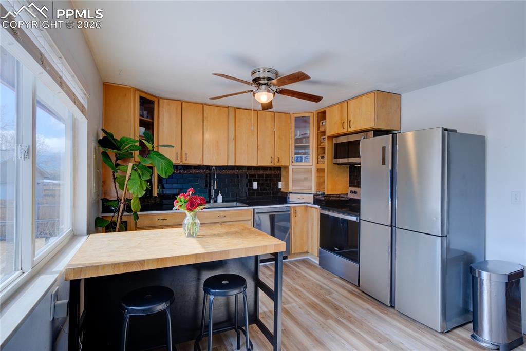 Kitchen featuring stainless steel appliances, glass insert cabinets, a kitchen bar, and butcher block counters