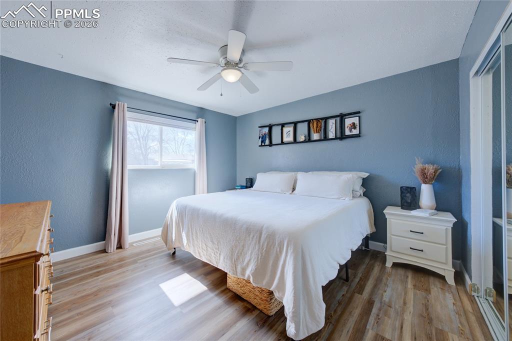 Bedroom featuring light wood-type flooring, ceiling fan, and a textured wall