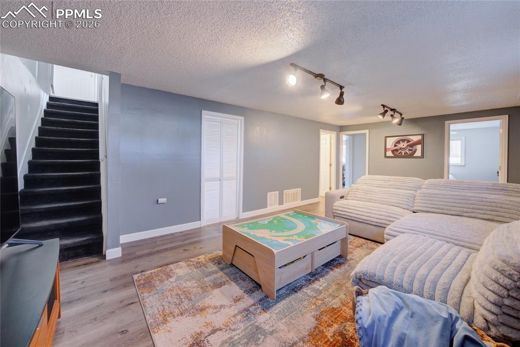 Living room featuring light wood-style flooring, a textured ceiling, and track lighting