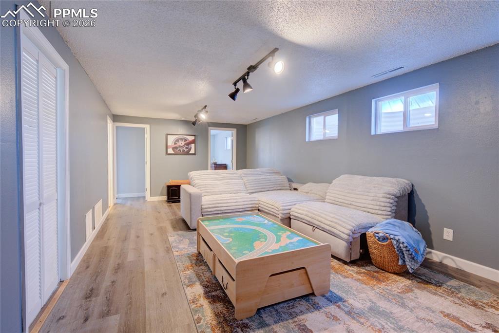 Living room featuring rail lighting, wood finished floors, and a textured ceiling