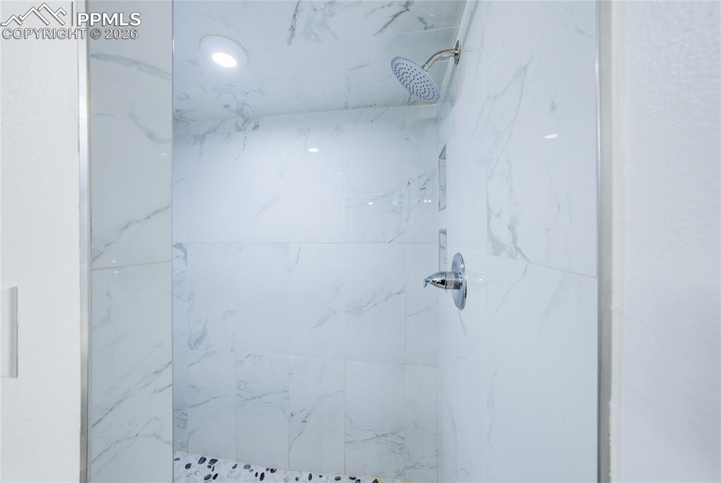 Full bath with a marble finish shower