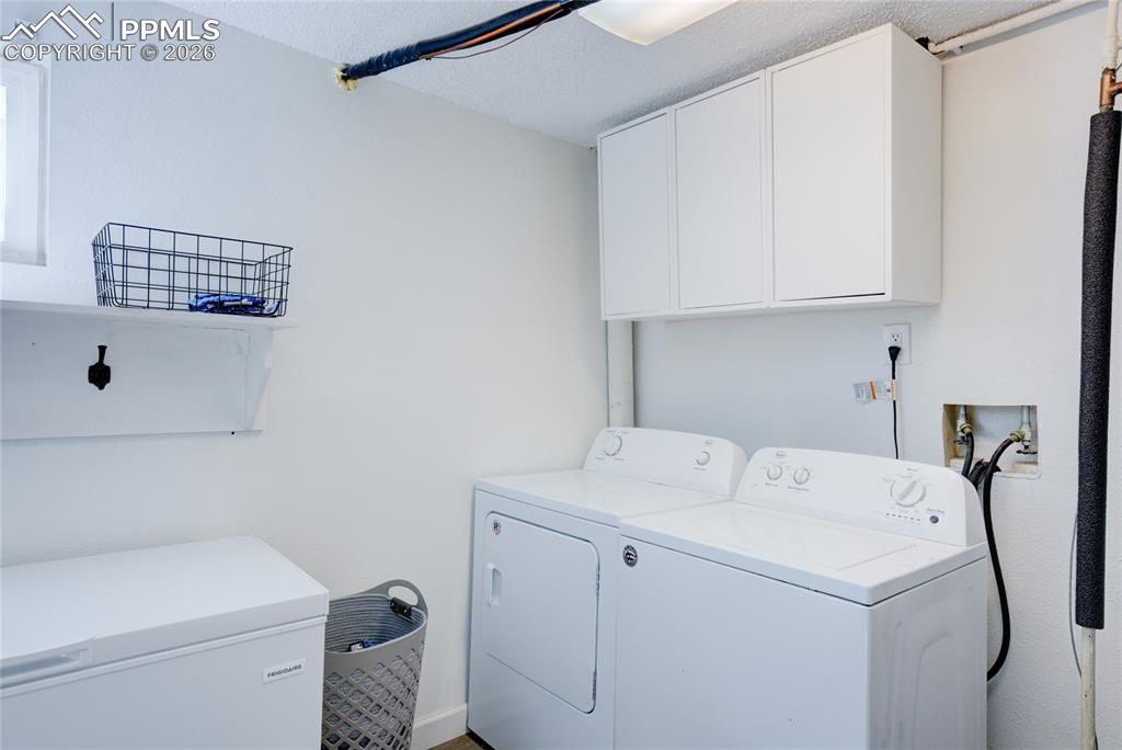 Laundry room featuring independent washer and dryer, cabinet space, and a textured ceiling