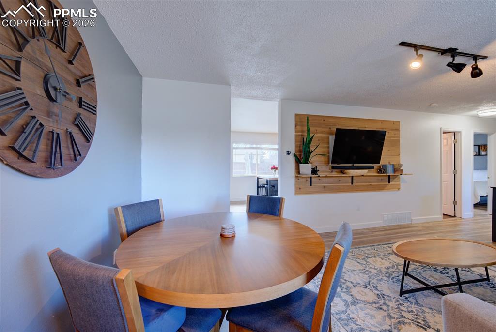 Dining space with a textured ceiling, wood finished floors, and track lighting
